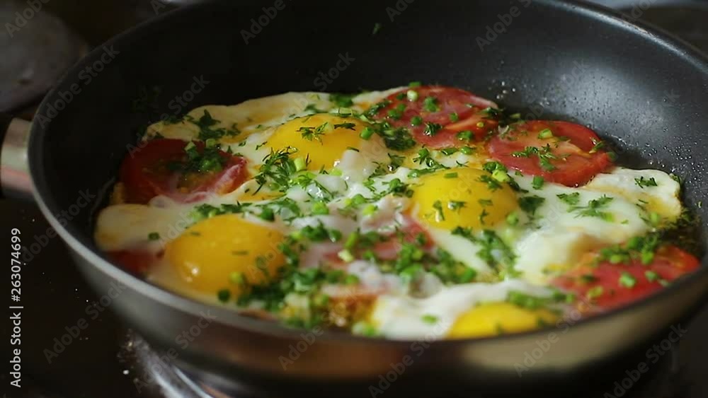 Cooking, Fry eggs in a pan with tomatoes and herbs close-up Cooking, Fry eggs in a pan with tomatoes and herbs close-up
