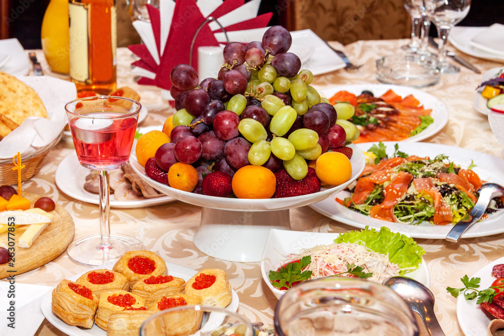 Luxurious table setting for a wedding or a holiday with beautiful fresh fruits and berries in a vase