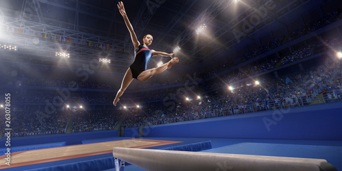 Female athlete doing a complicated exciting trick on gymnastics balance beam in a professional gym. Girl perform stunt in bright sports clothes © Alex