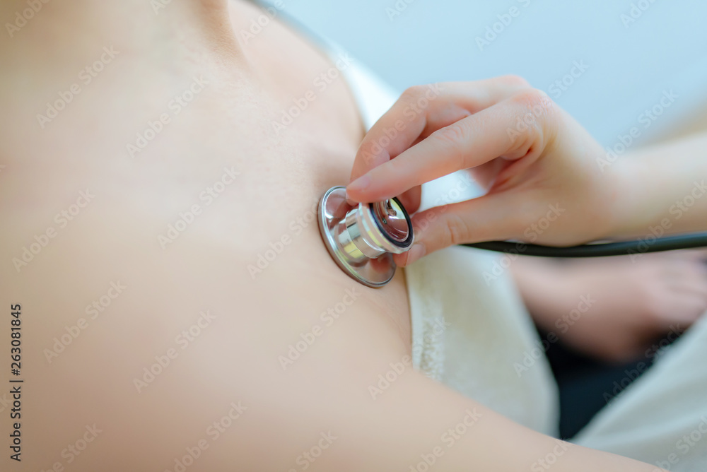 Fototapeta premium Frau wird mit Stethoskop untersucht