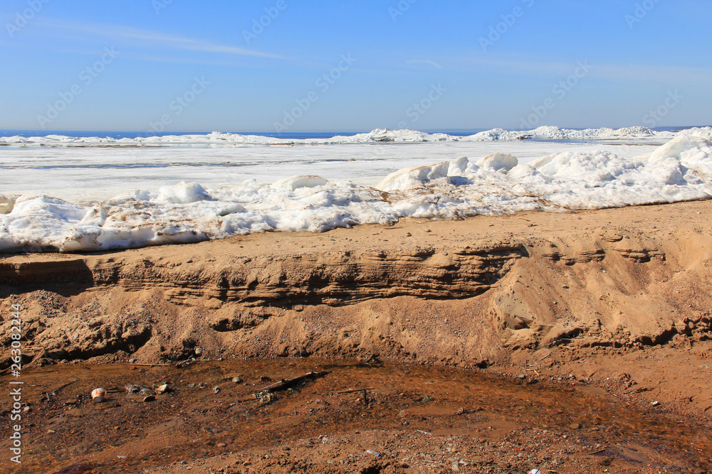 Snow and sand on the sea beach in spring