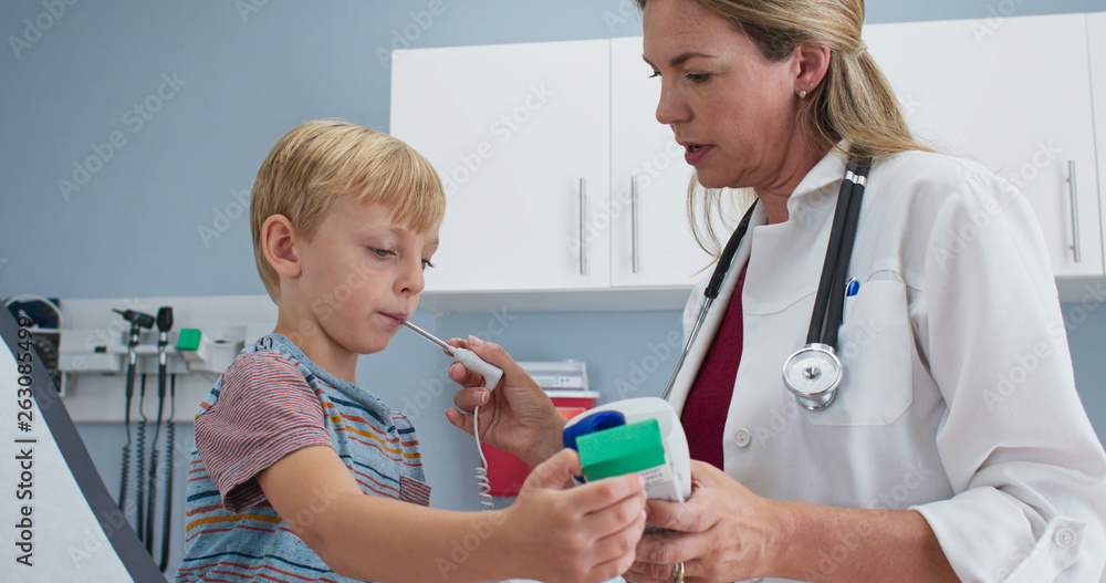 Female pediatrician using digital thermometer to check temperature of