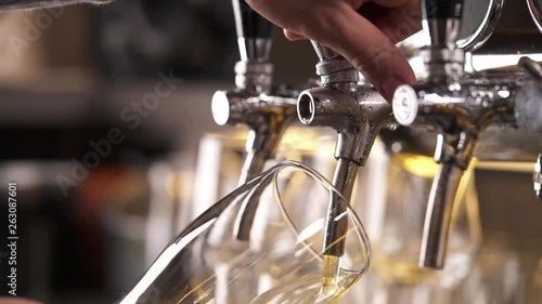 Top bottom shot of a bartenders hand holding a glass and pouring beer from tap. Close-up demonstration video
