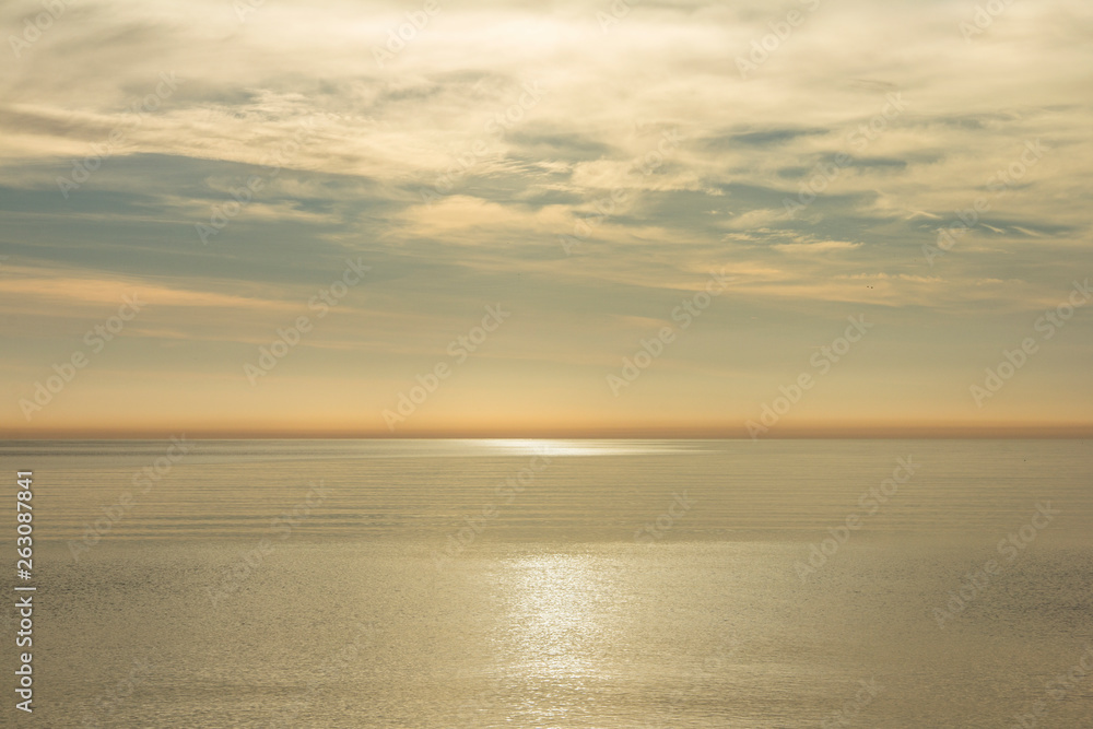Golden morning on the sea. Golden morning on the sea. Calm horizon at sunrise, the rays are hiding in the clouds reflecting in the light path on the water.