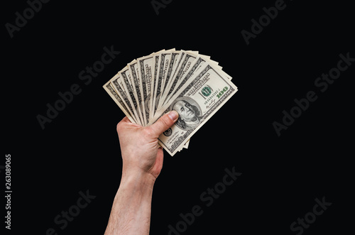 Man's hand holds american dollars money. On black background. Finance, earnings, crediting