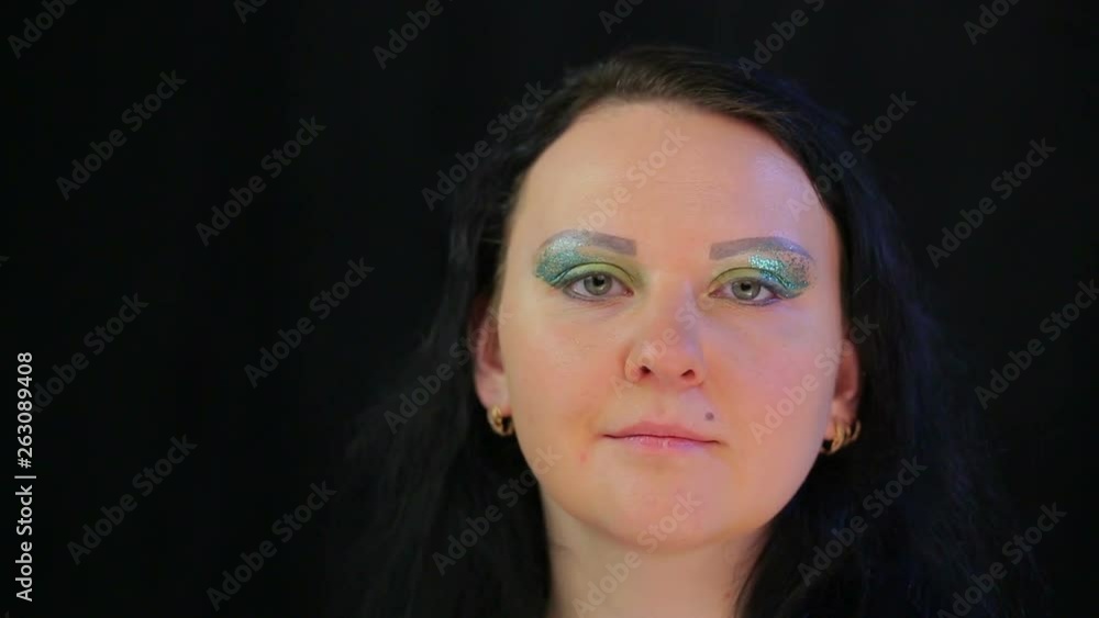 The face of a brunette woman with eye makeup bright green sparkles. The average plan The face of a brunette woman with eye makeup bright green sparkles. The average plan