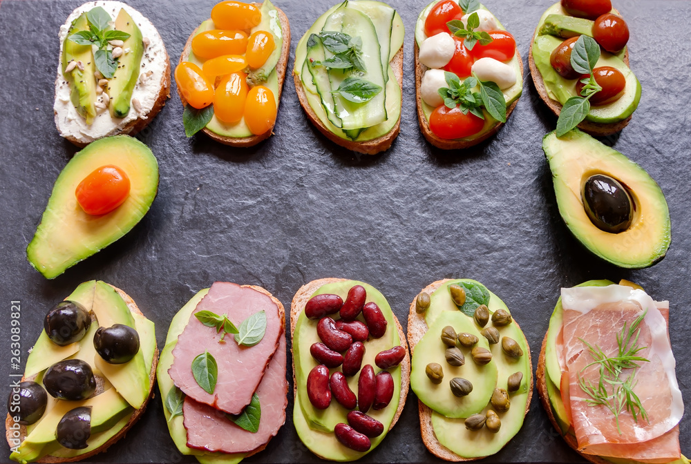 Avocado sandwich top view with fresh sliced avocados, ham meat, mozzarella, cheese and vegetables on black background flat lay. Concept keto diet snack Avocado sandwich top view with fresh sliced avocados, ham meat, mozzarella, cheese and vegetables on black background flat lay. Concept keto diet snack