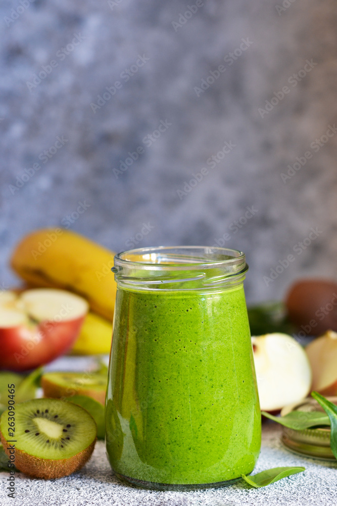 Green smoothie with banana, kiwi, apple and spinach on a concrete background. Detox menu. Green smoothie with banana, kiwi, apple and spinach on a concrete background. Detox menu.