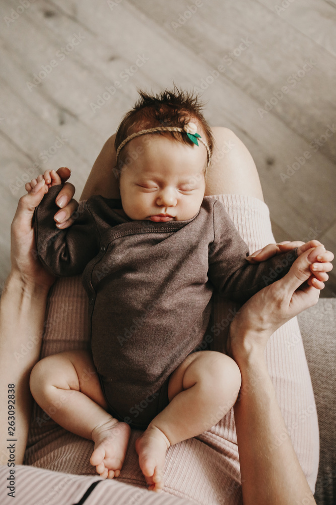 Mother is holding newborn baby on her knees. The kid is sleeping. Stock