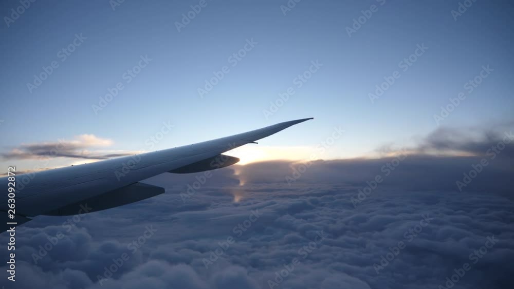 Airplane flight. Wing of an airplane flying above the clouds with sunset sky. View from the window of the plane. Aircraft. Traveling by air. Airplane flight. Wing of an airplane flying above the clouds with sunset sky. View from the window of the plane. Aircraft. Traveling by air.