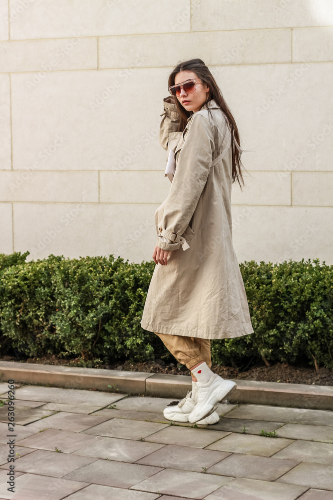 Portrait shooting of a stylish girl. Beige shades. Trends of spring and summer 2019. Pants of cork.Trench cloak, a wide jacket. Portrait shooting of a stylish girl. Beige shades. Trends of spring and summer 2019. Pants of cork.Trench cloak, a wide jacket.