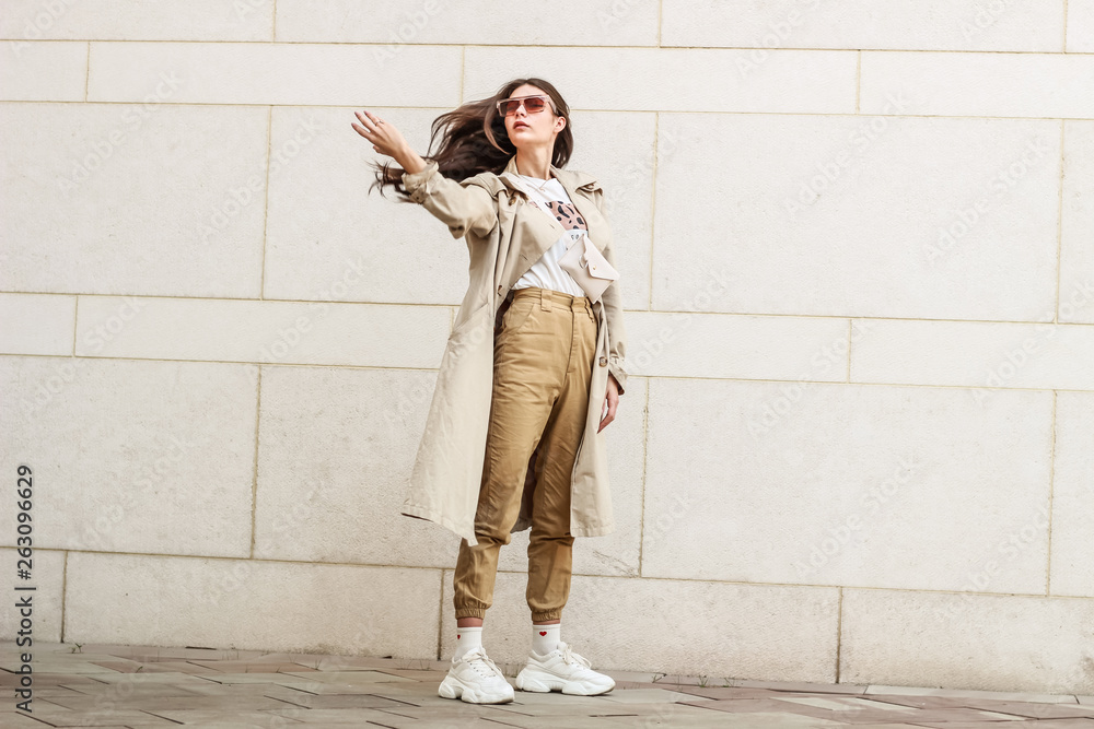 Portrait shooting of a stylish girl. Beige shades. Trends of spring and summer 2019. Pants of cork.Trench cloak, a wide jacket. Portrait shooting of a stylish girl. Beige shades. Trends of spring and summer 2019. Pants of cork.Trench cloak, a wide jacket.