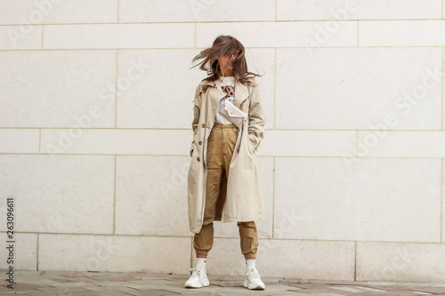 Portrait shooting of a stylish girl. Beige shades. Trends of spring and summer 2019. Pants of cork.Trench cloak, a wide jacket. photo