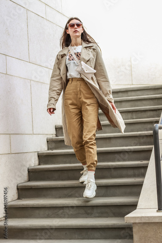 Portrait shooting of a stylish girl. Beige shades. Trends of spring and summer 2019. Pants of cork.Trench cloak, a wide jacket.