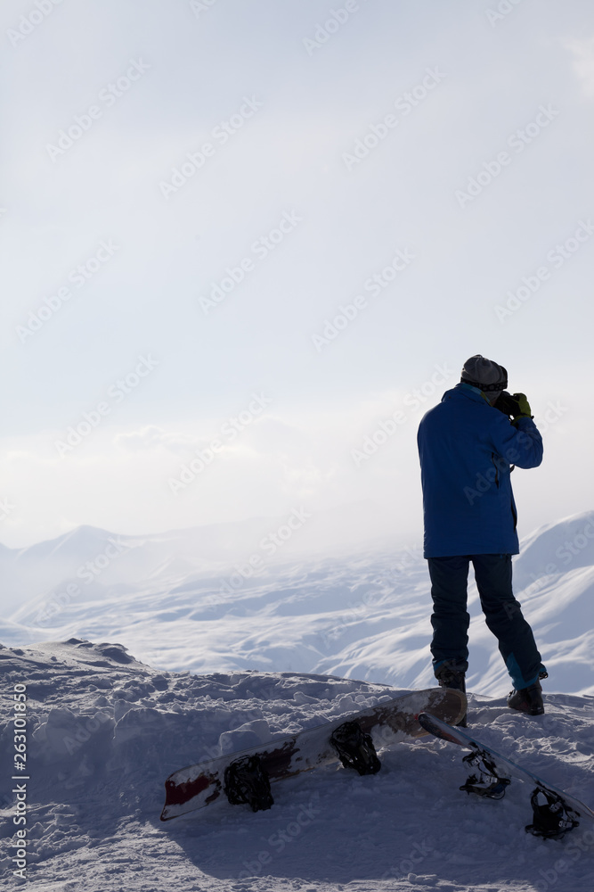 Skier makes photo on camera on top of snowy mountain