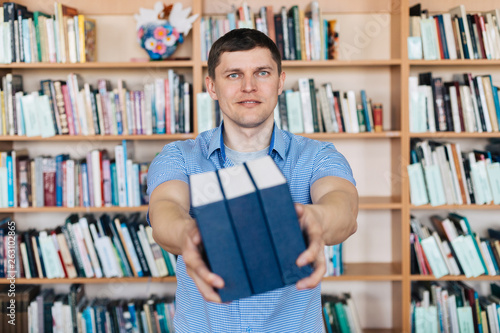 Male hands holding a stack of books. Man holds out a stack of books