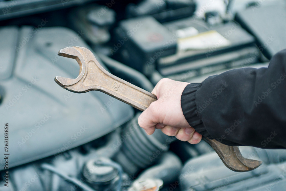 Hand of auto mechanic with a wrench. Car repair. Hand with wrench. Auto mechanic in car repair