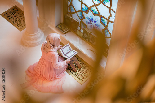 woman praying in the mosque and reading the Quran photo