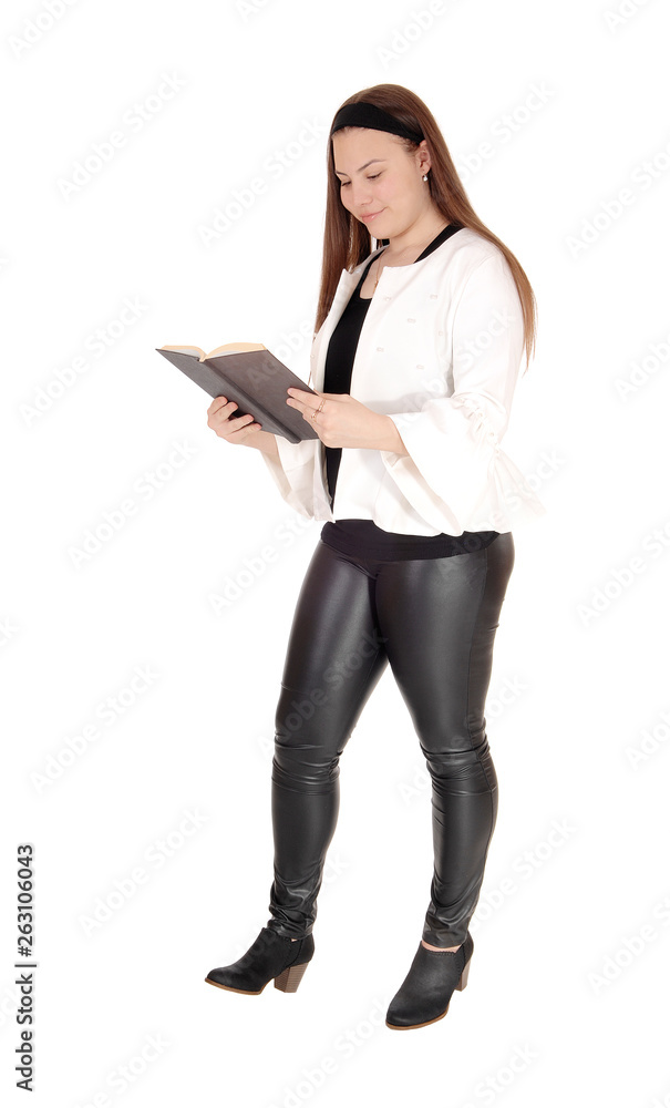 Teenage girl standing in pants holding a book in hands Teenage girl standing in pants holding a book in hands