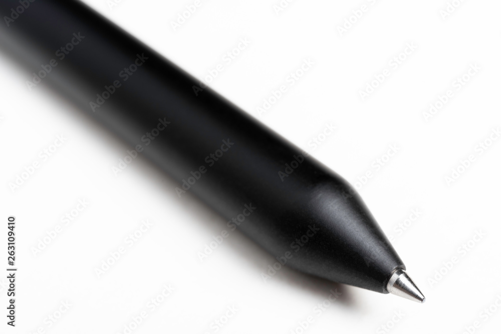 An extreme close-up or macro shot of a minimalist black barrel ballpoint pen with selective focus on tip set against plain white background. An extreme close-up or macro shot of a minimalist black barrel ballpoint pen with selective focus on tip set against plain white background.