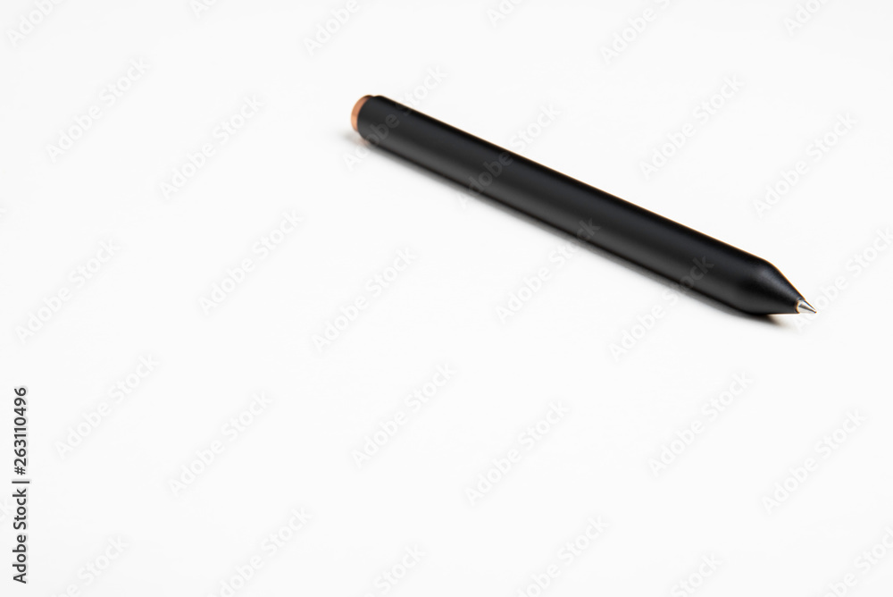 A close-up look with selective focus on a minimalistic barrel style clicker ballpoint pen set on a plain white background. A close-up look with selective focus on a minimalistic barrel style clicker ballpoint pen set on a plain white background.