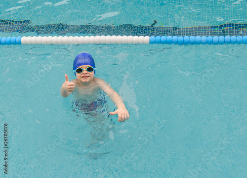 top view of a 7-year boy playing and swimming in the swimming pool smiling