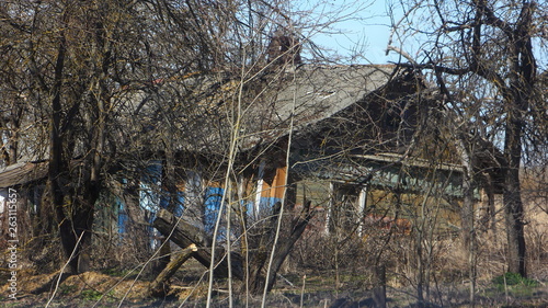 Abandoned rickety wooden house in a withered garden on derelict village