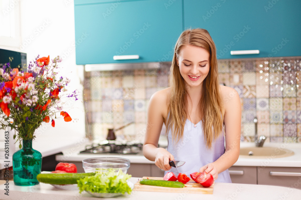 beautiful girl making salad in the kitchen