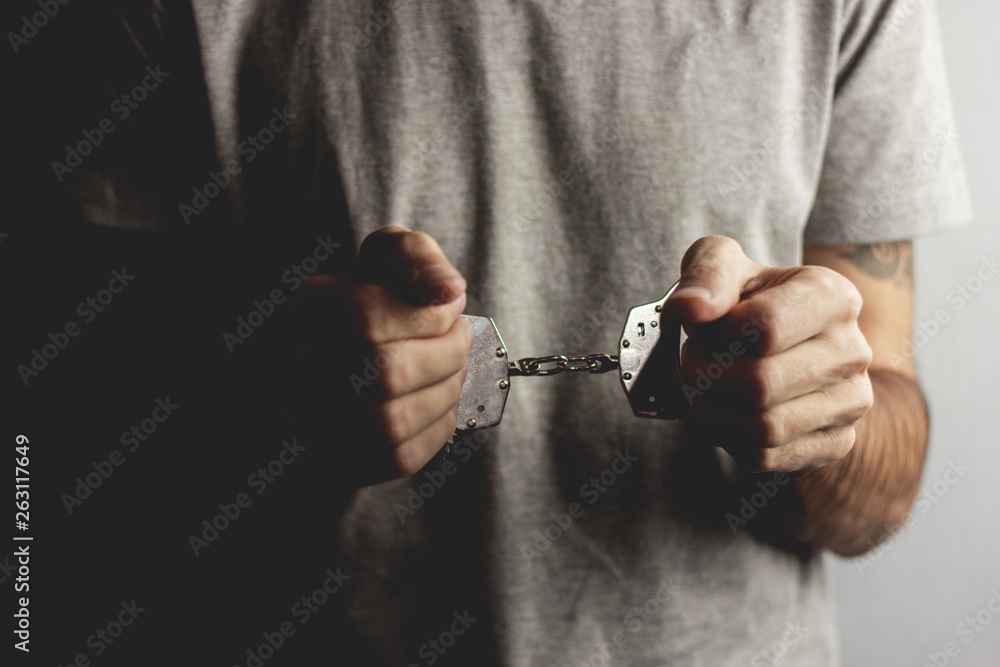 young man hand handcuffs on dark background young man hand handcuffs on dark background