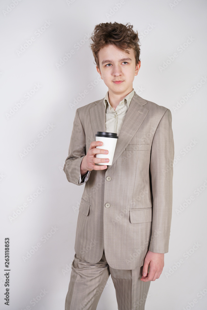 teenager male in gray business suit with paper Cup of coffee in hand on white studio background teenager male in gray business suit with paper Cup of coffee in hand on white studio background