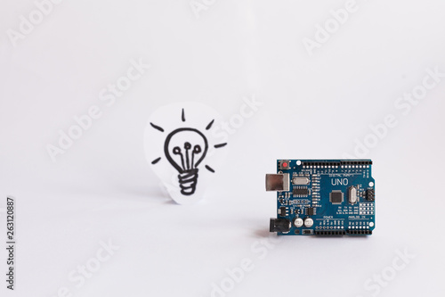 Arduino Uno. Arduino. Micro controller. Technology. Picture of a light bulb in the background. The science. White background.