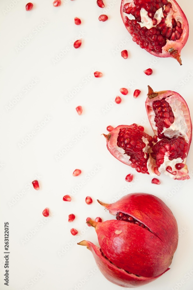 Pomegranate fruit berry on a white background. Cut pomegranate fruit. Red berries on the table. Juicy red fruits. Background with vitamins.