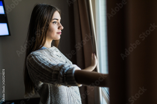 Beautiful woman opening curtains and looking through the window at home Free Download Beautiful woman opening curtains and looking through the window at home - GFXLoad