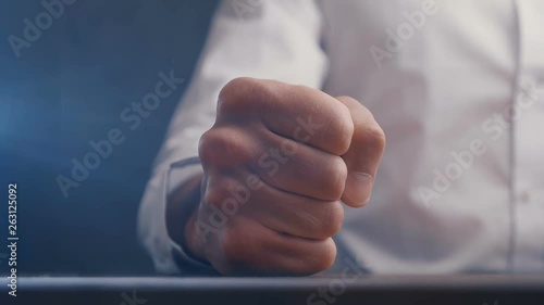 Fist of angry businessman beats on the table in slow motion