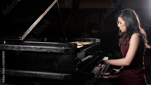 Beautiful young woman playing the piano in the concert hall, rehearsal