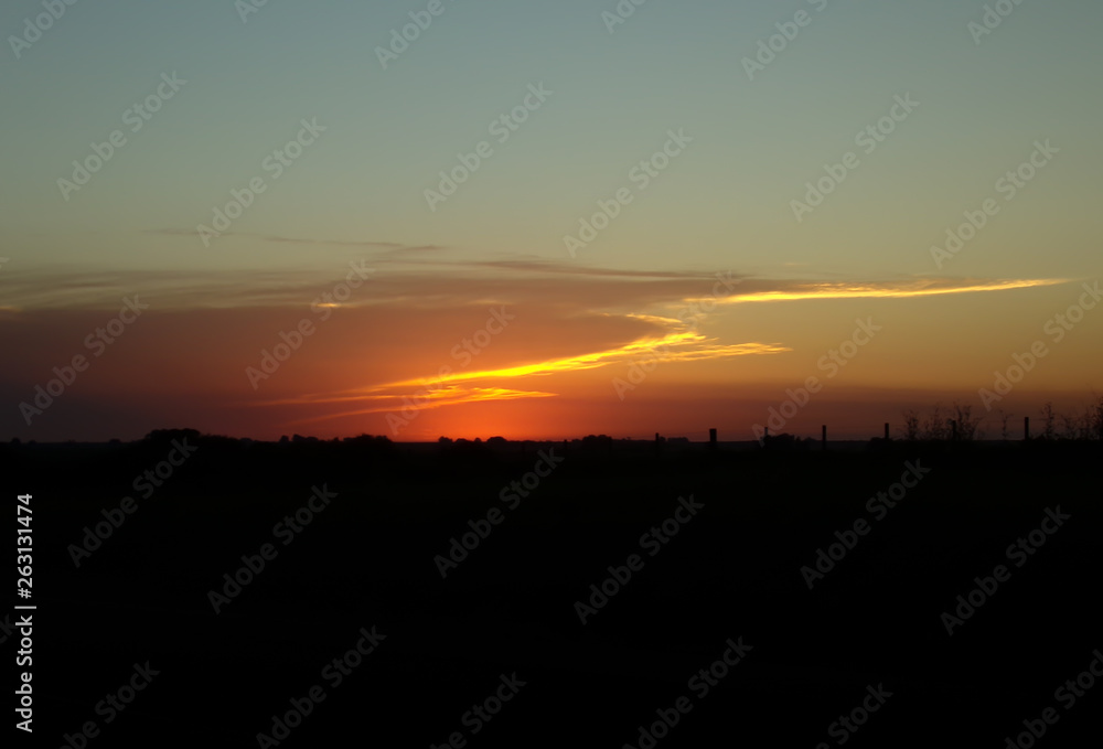 Bright Orange Sunset Landscape, country side on the road, sunrise, trees and plants in the dark