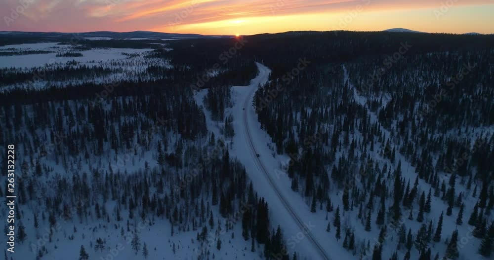 drone shot, following a vehicle, on a frozen route, between finnish woods and polar wilderness, in Pallas-yllastunturi national park, at the arctic circle, at sunset, on a sunny, winter evening dus drone shot, following a vehicle, on a frozen route, between finnish woods and polar wilderness, in Pallas-yllastunturi national park, at the arctic circle, at sunset, on a sunny, winter evening dus