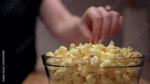 Close up static shot of glass bowl filled up with pop corns and couple reaching out for it enjoying some quality time together. Bonding concept, friendship and relationship. photo