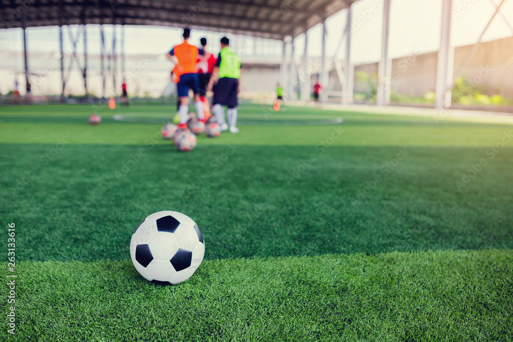 football on green artificial turf with blurry soccer team training football on green artificial turf with blurry soccer team training