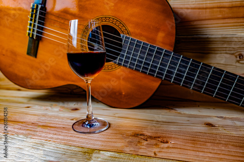 Old classical guitar on wooden background and a glass of wine