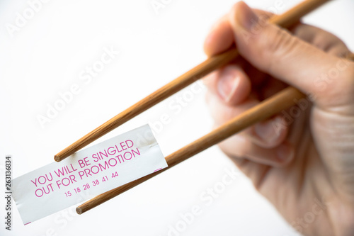 Chopsticks in hand, holding a cookie fortune "You will be singled out for a promotion."