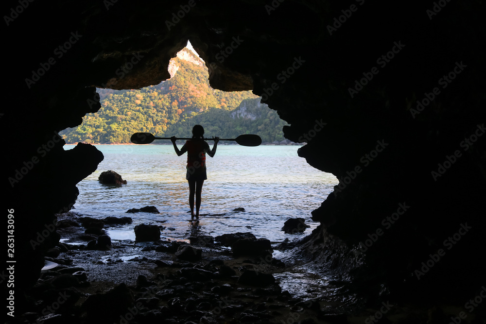 Kayaking in the cave, Asian girls holding the paddle stands in front of a cave by the sea. Kayaking in the cave, Asian girls holding the paddle stands in front of a cave by the sea.