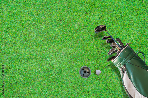 High angle view of golf bag, golf club, gloves and golf ball, with beautiful green lawn floor and golf hole as background With space to write the text.