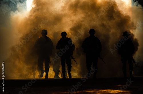 silhouette thai soldiers special forces team full uniform walking action through smoke and holding gun on hand