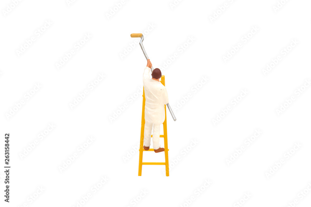 Fototapeta premium Miniature figurine character as painter standing on ladder and painting wall with paint tools isolated on white background.