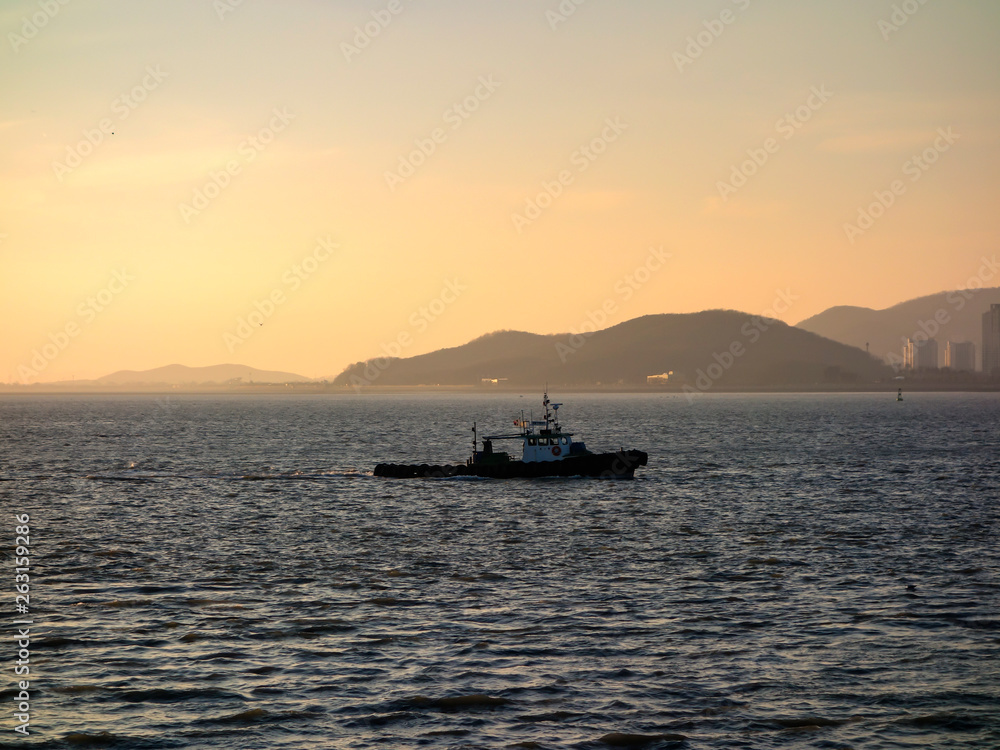 Incheon coastline, South Korea, under the background of sunset and blue sky, with ships sailing, city horizon.