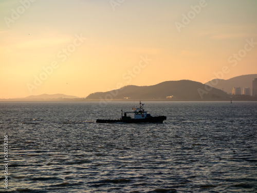 Incheon coastline, South Korea, under the background of sunset and blue sky, with ships sailing, city horizon. © Xiangli