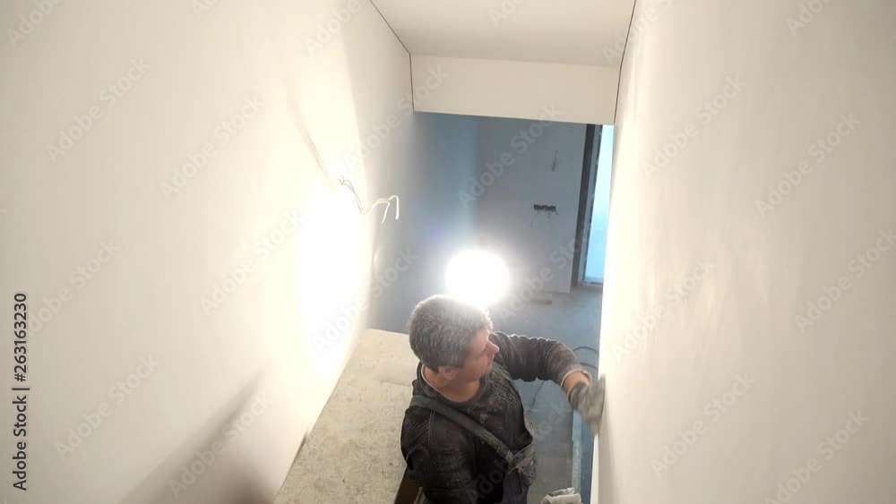 Home improvement worker with gloves working with sander for smooth wall surface Home improvement worker with gloves working with sander for smooth wall surface