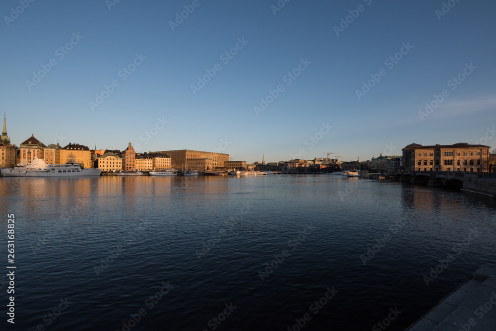 A sunny early spring day in Stockholm, view over a pier with boats and birds at the old town and the Södermalm district 