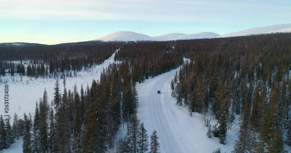 Aerial, reverse, drone shot, over spruce forest, buildings and Ounastunturit fjells, in Pallas-yllastunturi national park, at the arctic circle, on a sunny, winter evening, in Muonio, Lapland, Finland Aerial, reverse, drone shot, over spruce forest, buildings and Ounastunturit fjells, in Pallas-yllastunturi national park, at the arctic circle, on a sunny, winter evening, in Muonio, Lapland, Finland